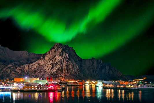 Breathtaking view of a Norwegian fjord with crystal-clear blue waters, lush green mountainsides, and a charming coastal village nestled by the shore